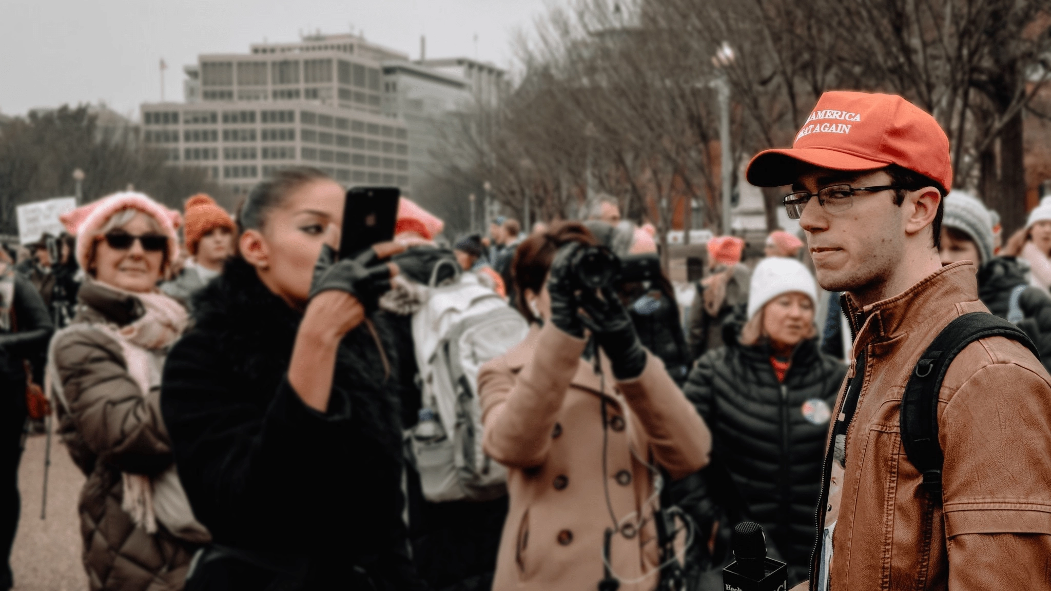 John Doyle looking at viewer in front of blurry crowd of protesters
